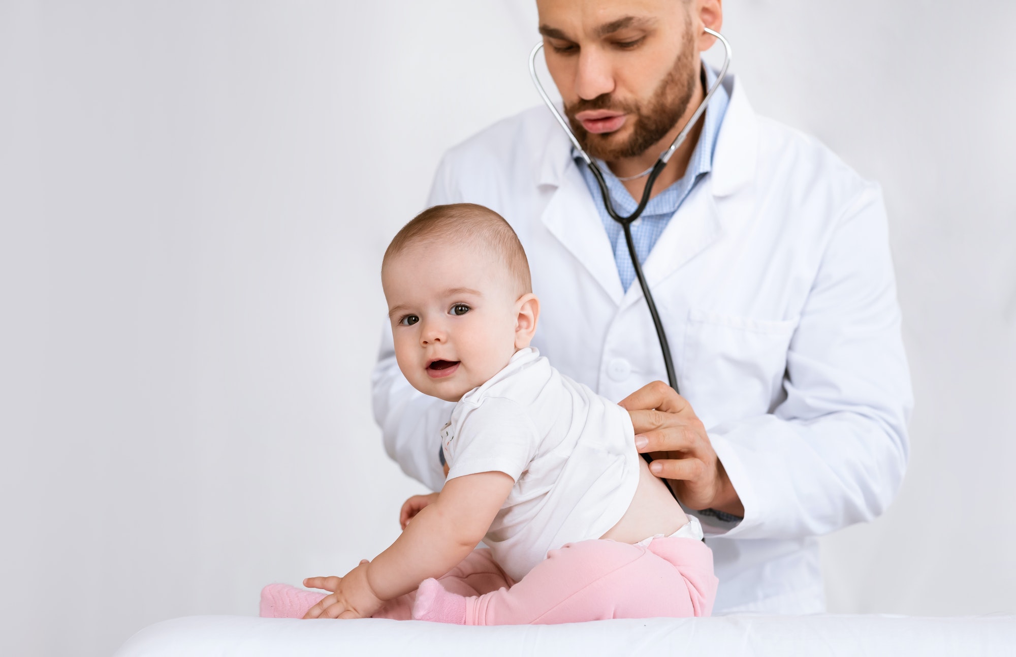 Doctor Examining Baby Listening To Her Lungs Over White Background
