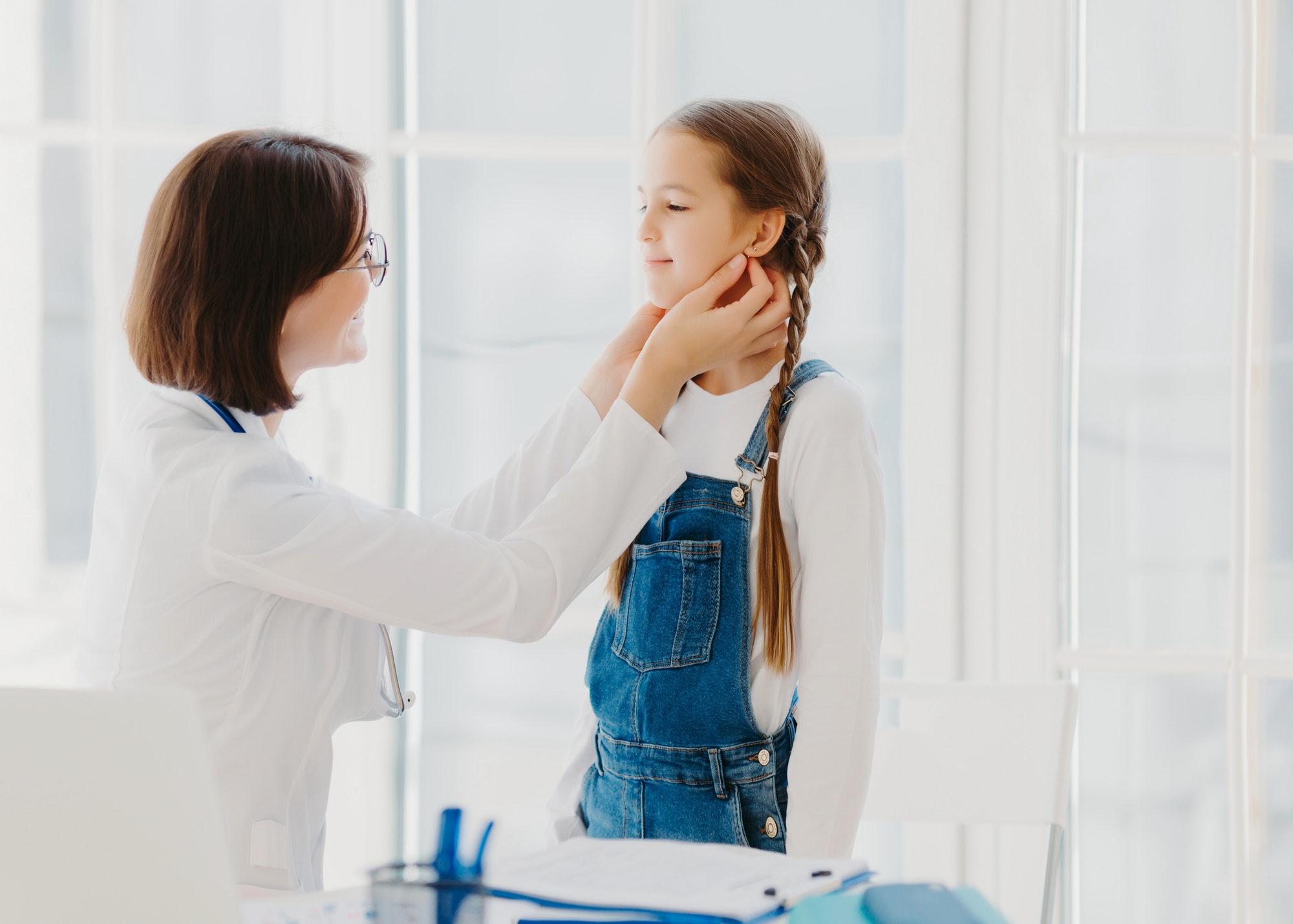 Female pediatrician examines childs throat, being professional skilled pediatrician, consults