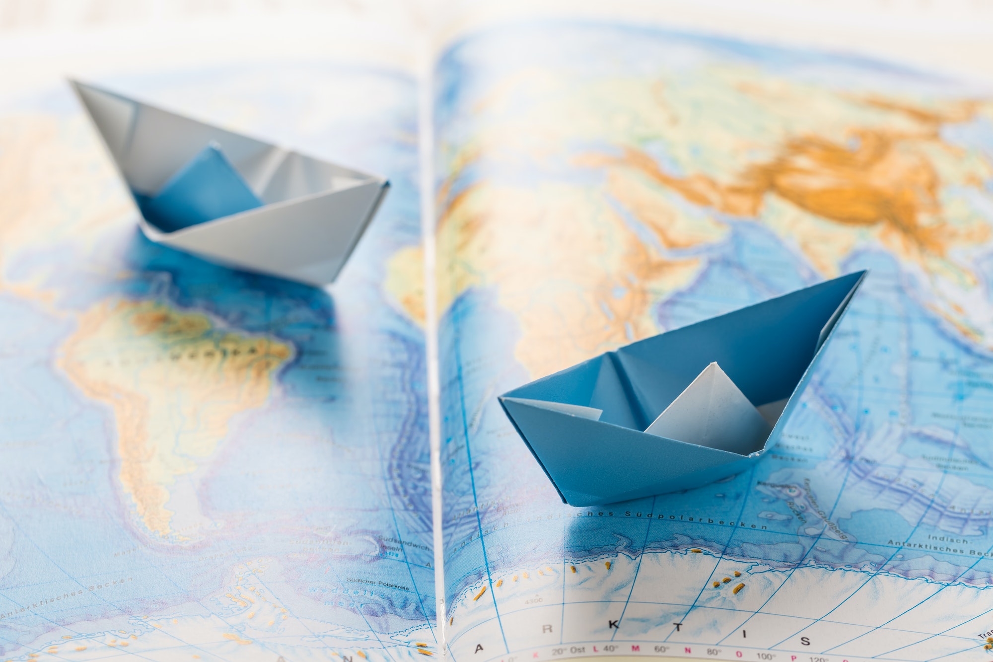 Paper boats on world map. Concept of traveling or military exercise.