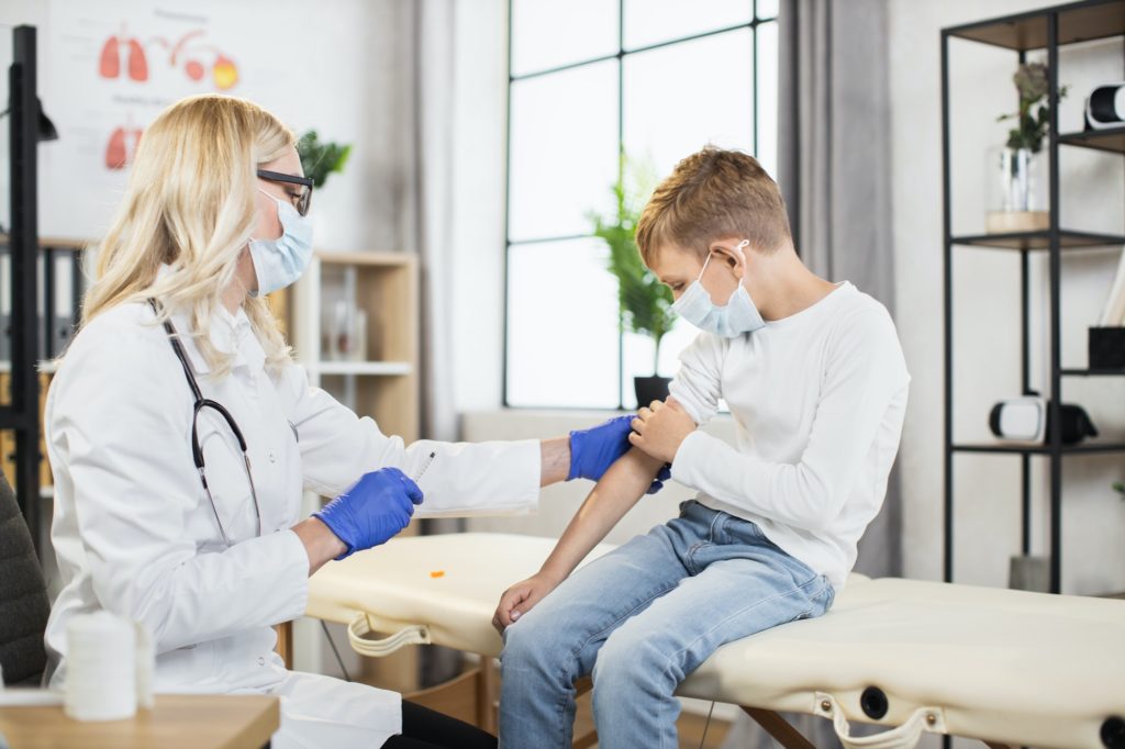 Caucasian boy getting vaccine by female doctor at hospital