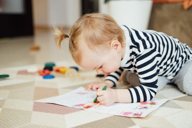 Little girl draws with pencils. Child development.