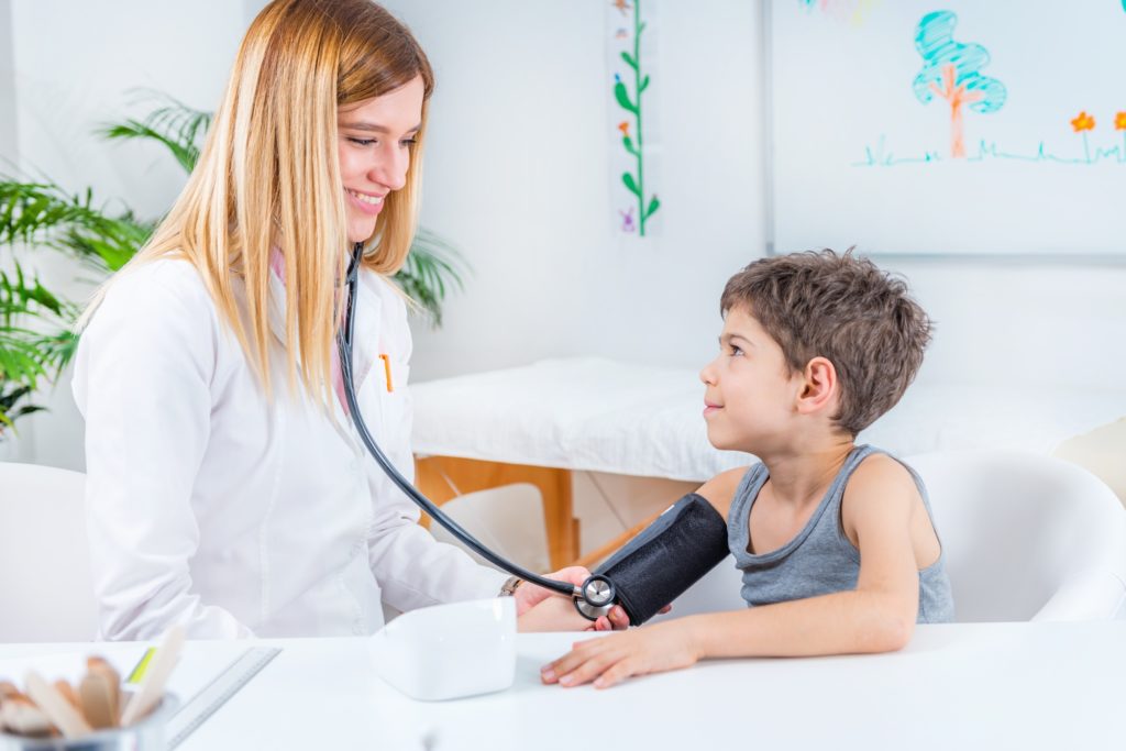 Pediatrician measuring boy’s blood pressure