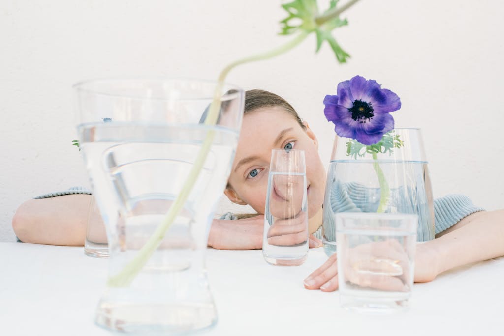Creative portrait featuring a woman seen through glass with a purple flower.