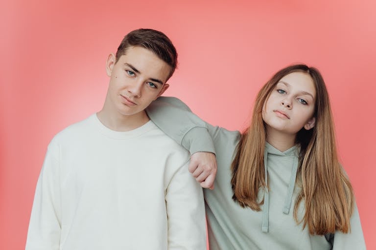 Portrait of stylish teenagers against a pink studio backdrop.